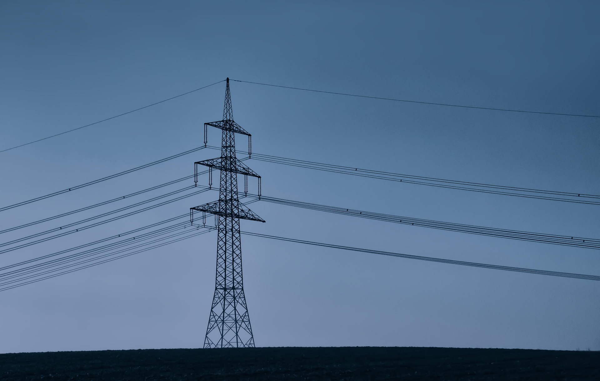 Transmission pylon and power lines against a blue dusk sky
