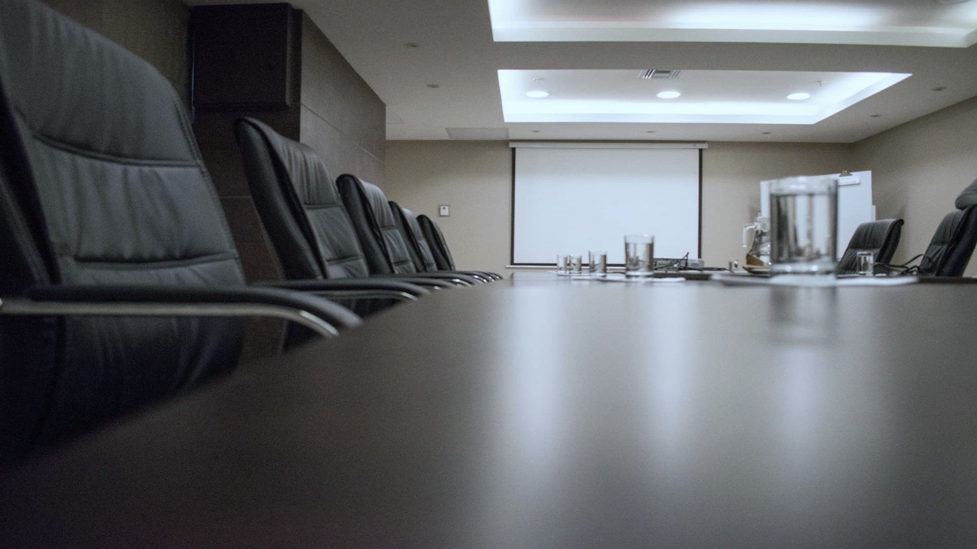 Empty boardroom with a long table and leather chairs, shot low along the table