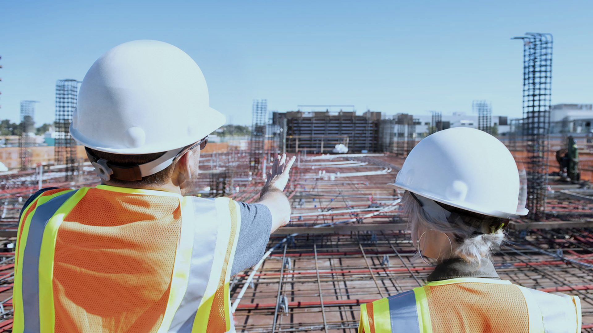 Two site leaders in hi-vis looking out over a rebar deck on a construction site